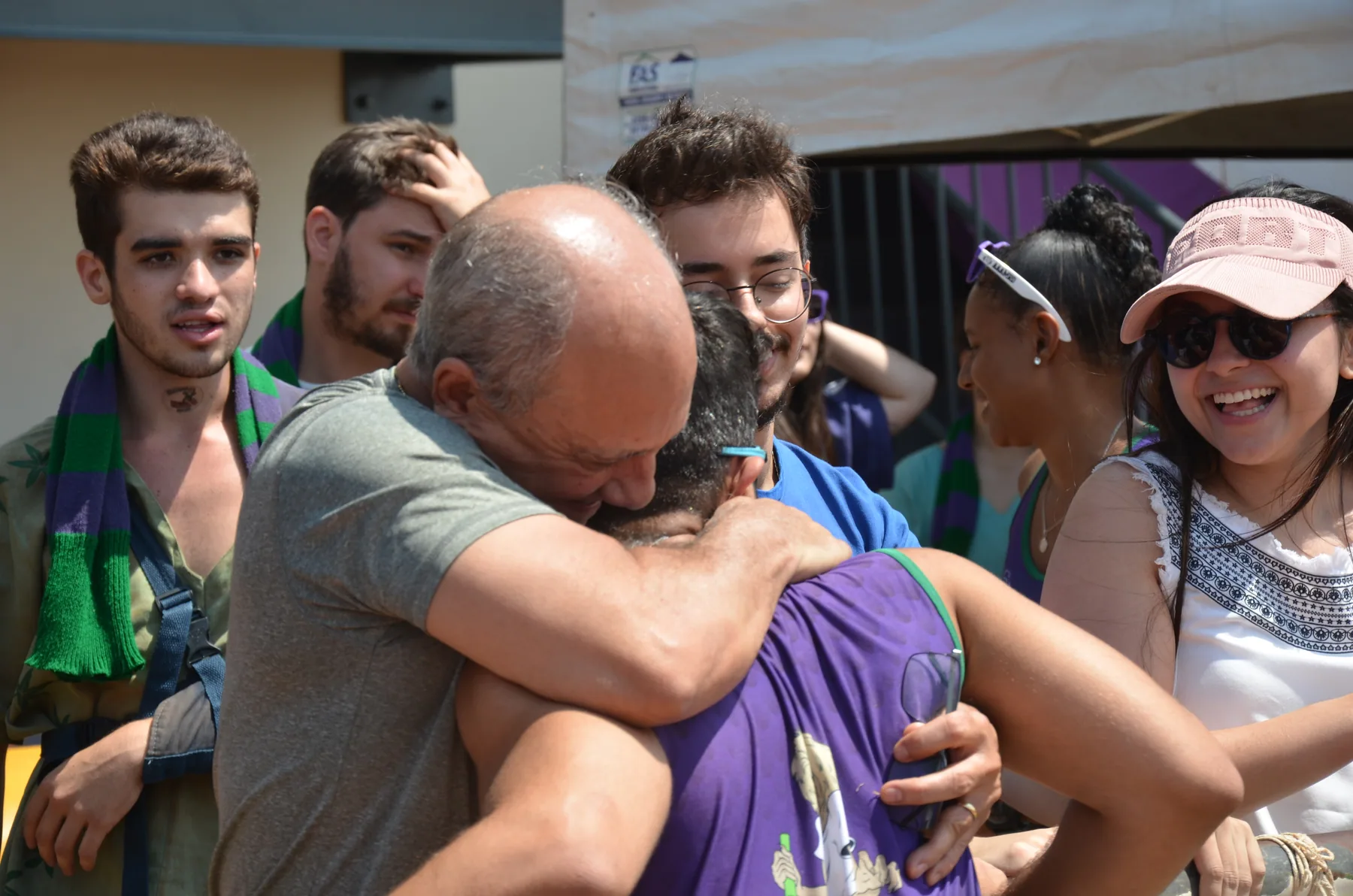 Participantes da Olimpíada UFU 2024 se abraçam após uma prova de atletismo, cercados por colegas e torcida.